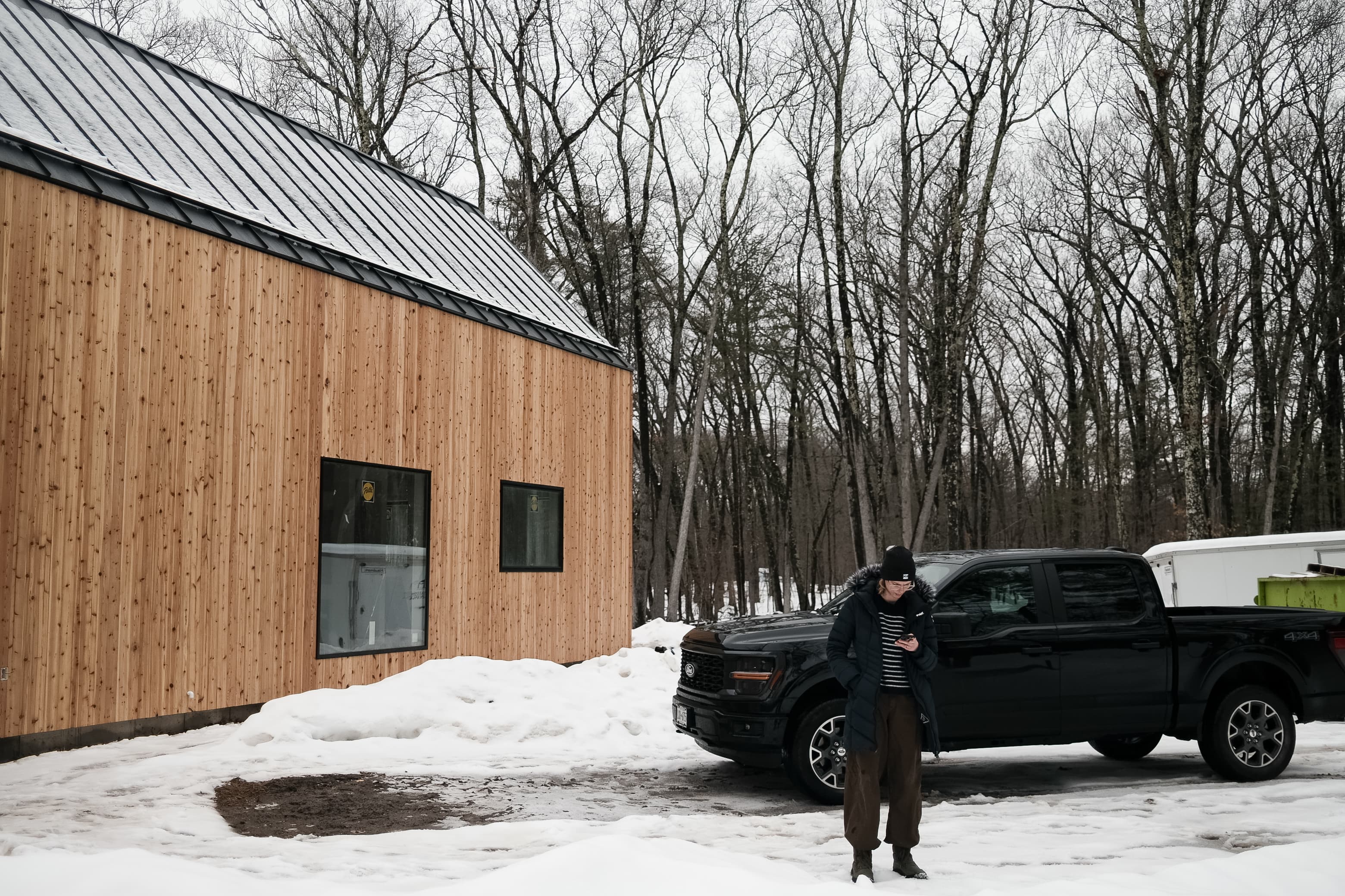 Amanda standing by the truck outside the cabin in winter snow